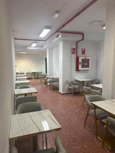 un aula vacía con mesas y sillas en una habitación en just hostel capsules, en Alicante
