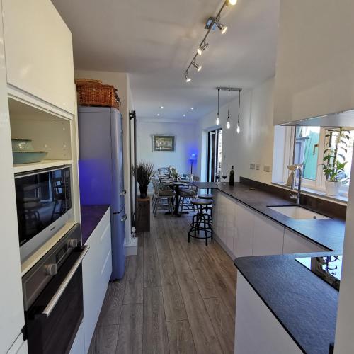 a kitchen with white cabinets and a counter top at AnchorageWells Entire Cottage for 8 with 4 King Ensuite Rooms in Wells next the Sea