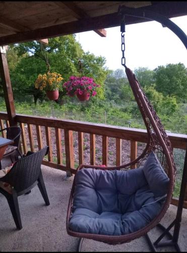 a swinging chair on a porch with flowers at Planinska kuca in Rap