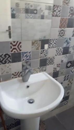 a white sink in a bathroom with tiles on the wall at الحي الاول 6 اكتوبر مجاورة 3 in 6th Of October