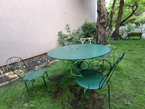une table et des chaises vertes dans la cour dans l'établissement Loft cosy avec balcon et jardin, à Aubervilliers