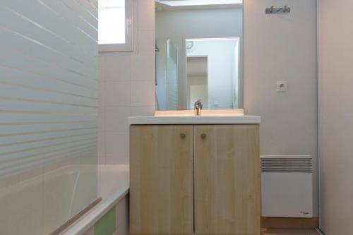 une salle de bain avec un lavabo, une baignoire et un miroir dans l'établissement maison piscine proche plage, à Ondres