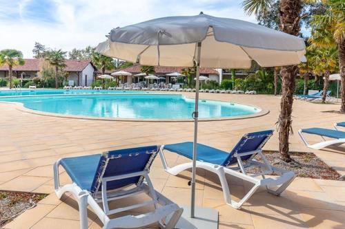 deux chaises et un parasol à côté d'une piscine dans l'établissement maison piscine proche plage, à Ondres