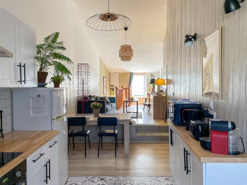 une cuisine avec des armoires blanches et un salon dans l'établissement Maison cosy et atypique, à Arzens