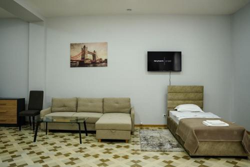1 dormitorio con cama, sofá y TV en Square Inn en Gyumri