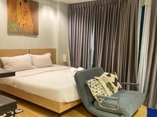 a bedroom with a bed and a chair in front of a window at Grand Blue Condominium by Mary in Mae Pim