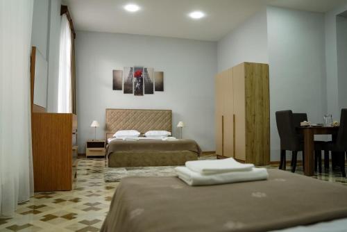 Cette chambre comprend deux lits et un bureau. dans l'établissement Square Inn, à Gyumri