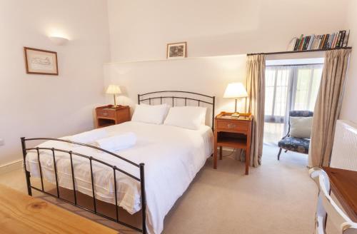 um quarto com uma cama, uma cadeira e uma janela em Harthanger View Cottage, Luxborough em Luxborough
