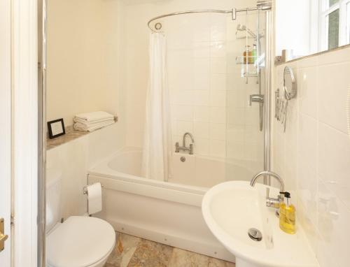 a white bathroom with a toilet and a sink at Coachman's Cottage, West Porlock in Porlock