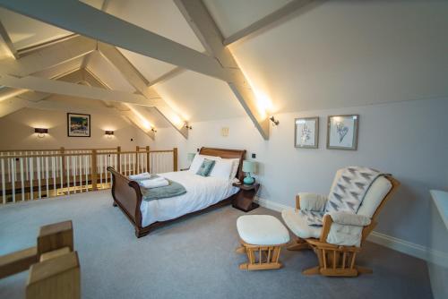 a bedroom with a bed and two chairs in it at The Cowshed in Clatworthy