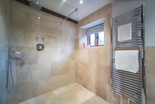 a bathroom with a shower with a glass door at The Cowshed in Clatworthy