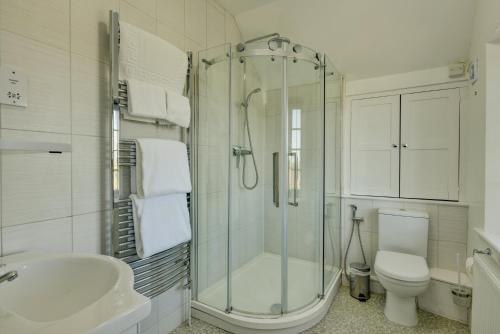 a bathroom with a shower and a toilet and a sink at Coach House in Washford