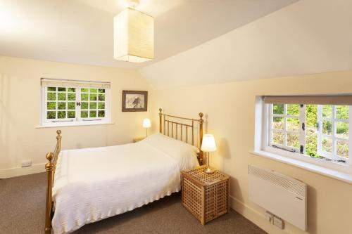 a bedroom with a bed and two windows at Worthy Cottage in Porlock