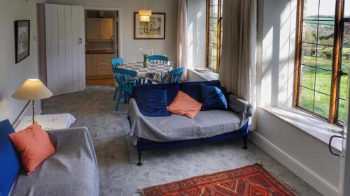 a living room with a chair and a table and windows at Barn Cottage, Brayford in Charles