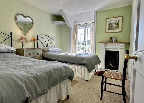 1 Schlafzimmer mit 2 Betten, einem Kamin und einem Spiegel in der Unterkunft Orchard Cottage in Charles