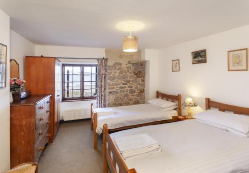 a bedroom with two beds and a dresser and a window at The Crows Nest in Porlock