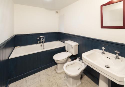 a bathroom with a toilet and a tub and a sink at The Crows Nest in Porlock