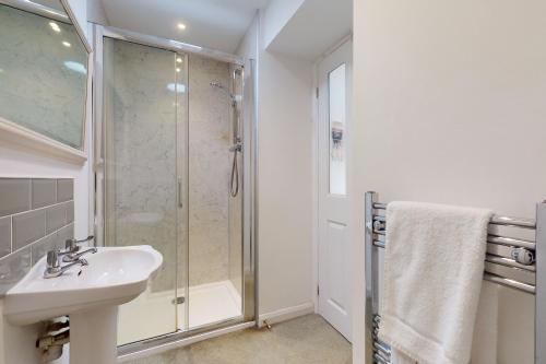 a white bathroom with a shower and a sink at Plum Tree Cottage, Porlock in Porlock