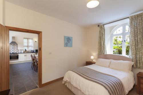 a bedroom with a bed with a window and a kitchen at The Mill House in Bampton