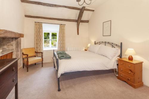 a bedroom with a bed and a chair and a window at Old Church House, Brayford in Highbray