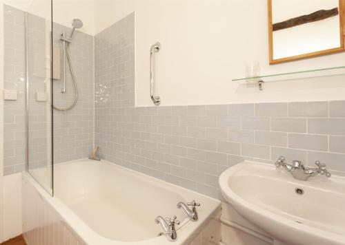 a bathroom with a shower and a tub and a sink at Old Church House, Brayford in Highbray