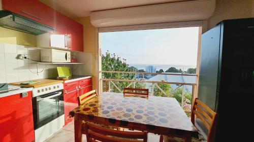 a kitchen with a table and a balcony with a view at La Marina Créole in Gourbeyre