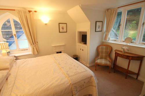 a bedroom with a bed and a desk and windows at Dunkery Apartment in Porlock