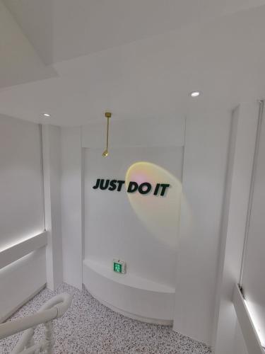 a white bathroom with ajust do it sign on the wall at Urban Stay Anyang in Anyang