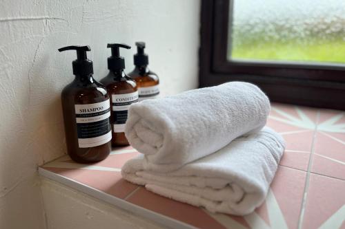duas garrafas de sabão e toalhas num balcão da casa de banho em Jasper Cottage Hawkridge em Dulverton