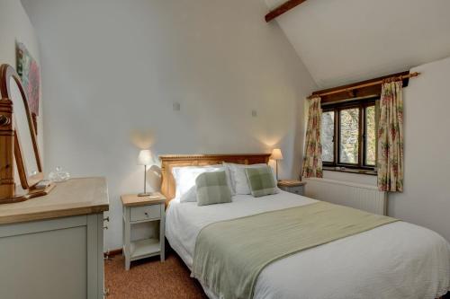 a bedroom with a bed and a desk and a window at The Shippon in Wheddon Cross