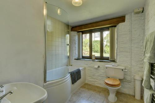 a bathroom with a tub and a toilet and a sink at The Shippon in Wheddon Cross
