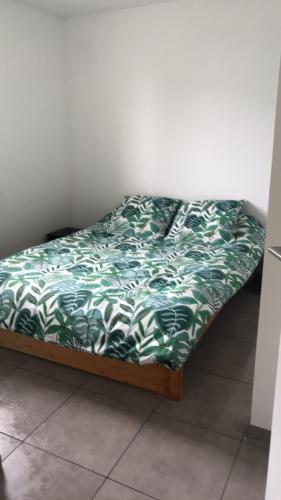 Ce lit se trouve dans un dortoir doté d'une couverture verte et blanche. dans l'établissement entre terre et mer, à Saint-Pol-de-Léon