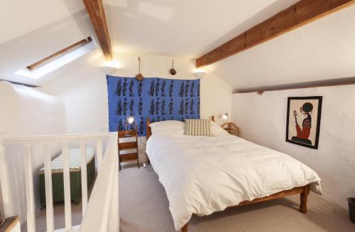- une chambre avec un lit blanc et une fenêtre bleue dans l'établissement Garden Cottage, Wiveliscombe, à Wiveliscombe