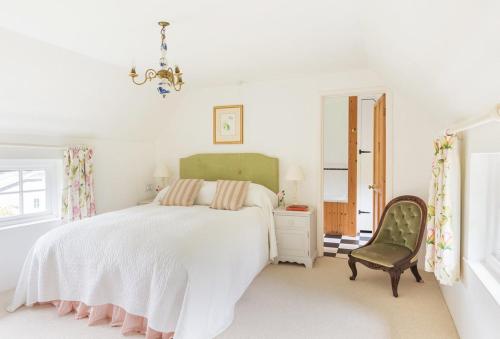 Bratton FlemingにあるBratton Mill Cottageの白いベッドルーム(ベッド1台、椅子付)