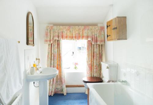ein Badezimmer mit Waschbecken, Badewanne und Fenster in der Unterkunft Bratton Mill Farmhouse in Bratton Fleming
