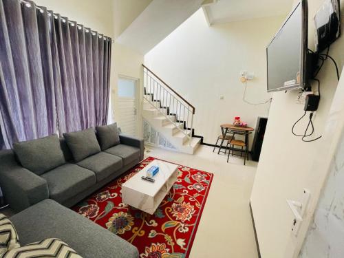 ein Wohnzimmer mit Sofa und Fernseher in der Unterkunft Villa Tanjung Alam Batu Syariah in Tlekung