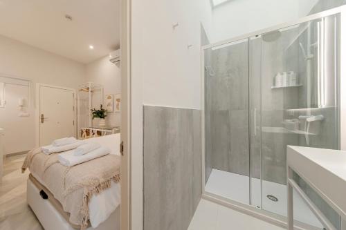 uma casa de banho com uma cabina de duche ao nível do chão e um lavatório. em Indulge Group: Downtown Cuna 1.0 em Sevilha