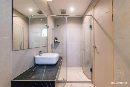 a bathroom with a sink and a glass shower at Aru Suites Kota Kinabalu in Kota Kinabalu
