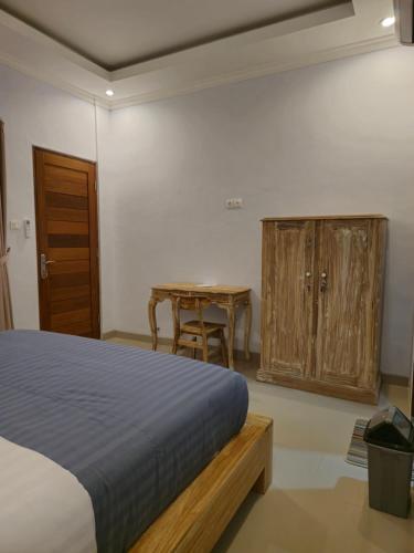 ein Schlafzimmer mit einem Bett, einem Tisch und einem Holzschrank in der Unterkunft The Lucky Canggu 2 in Canggu