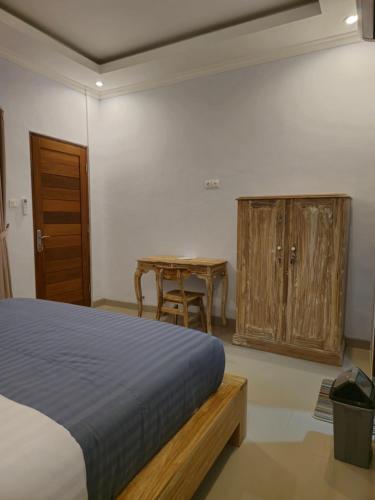 a bedroom with a bed and a table and a wooden cabinet at The Lucky Canggu 2 in Canggu