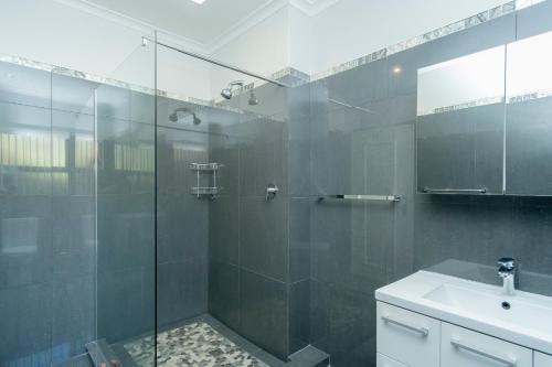 uma casa de banho com uma cabina de duche em vidro e um lavatório. em Hout Bay Hilltop em Hout Bay