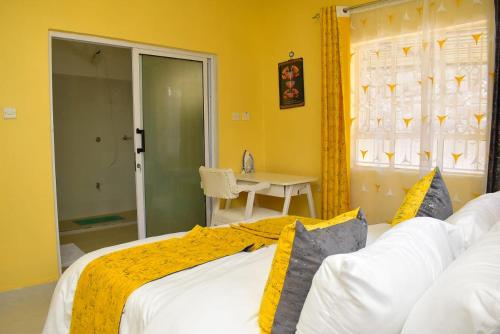 a bedroom with a white bed with a yellow blanket at Aggie's BnB in Nakuru