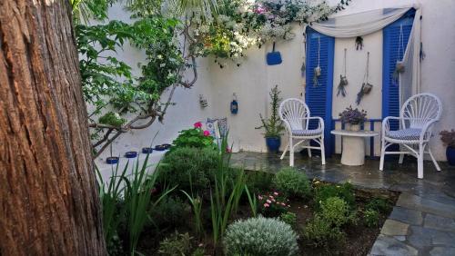 d'un jardin avec des chaises, une table et des portes bleues. dans l'établissement Small traditiional home near the shops and restaurants in Korissia, Kea, à Ioulída