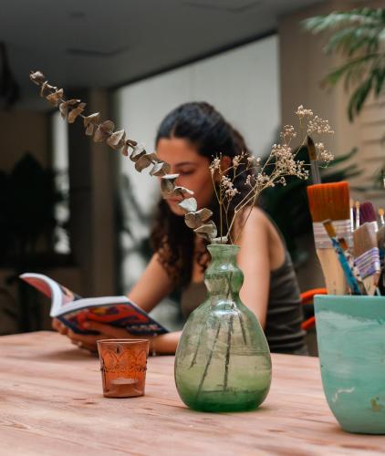 a woman sitting at a table with a vase with flowers at Boutique Nest in New Cairo in Cairo