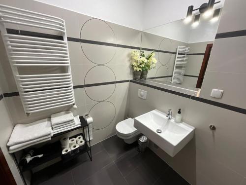 a bathroom with a white toilet and a sink at Apartamenty Złota Nić in Opole