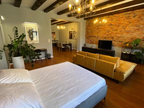 a bedroom with a bed and a couch and a brick wall at Apartamenty Złota Nić in Opole