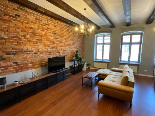 a living room with a couch and a brick wall at Apartamenty Złota Nić in Opole