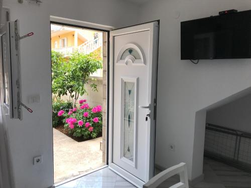 une porte menant à une terrasse ornée de fleurs roses dans l'établissement Apartment K2, à Radanovići