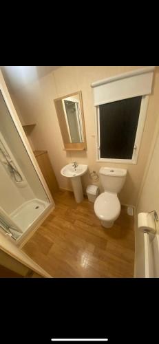 La salle de bains est pourvue de toilettes, d'un lavabo et d'un miroir. dans l'établissement Static Caravan Marine Holiday Park, à Rhyl