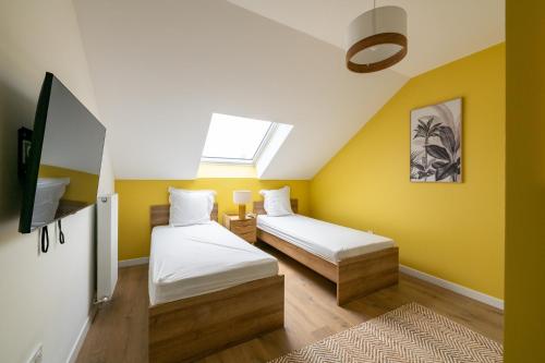 2 camas en una habitación con paredes amarillas en Élégance & Confort pr 6 à Disney - Fairytale Factory en Saint-Germain-sur-Morin